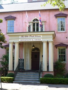 an old pink house with white pillars and flags on the front door is featured in this postcard