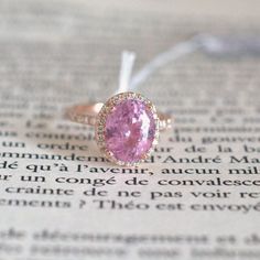 a close up of a pink stone ring on top of an open book with words in the background