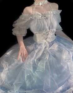 a woman in a white dress is sitting on a blue cloth with her hands behind her back