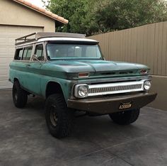 an old pick up truck parked in front of a garage with a roof rack on it