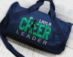 This personalized CHEER travel bag with Shimmer Green applique is ready to hold all your stuff whether for after school practice, competitions or even a weekend at grandma's! Add a name for a super personalized on the go bag. With a design you won’t find anywhere else, Persunly duffle bags show off your favorite activity, while keeping all your gear handy and protected. Our three sizes are roomy and fit shoes, clothing, balls, and small sporting equipment. Made from a sturdy denier polyester canvas, and with tough zippers and straps, these totes and duffles are built to last. CUSTOM BAG OPTIONS: Custom bag style: Tote, Small Duffle, or Large Duffle. Dimensions listed below. Custom bag color: Drop down menu options are available based on what coordinates with the design colors. Not all desi Personalized Sporty School Bag, Sporty Personalized School Bag, Customizable Sporty School Bags, Sporty Customizable School Bags, Personalized Bags For Everyday School Use, School Spirit Personalized Bags For Everyday Use, Customizable School Spirit Bag For Everyday, Customizable School Spirit Bags For Everyday Use, Personalized School Spirit Bags