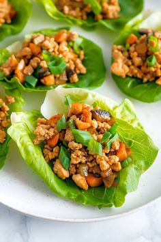 several lettuce leaves with meat and vegetables in them sitting on a white plate