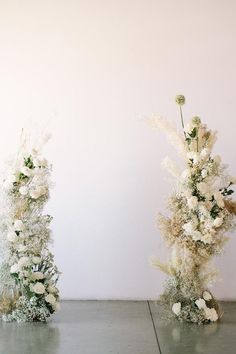 two vases with white flowers are on the floor