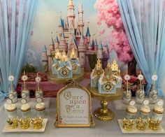 there are many cupcakes and cakes on the table in front of the castle