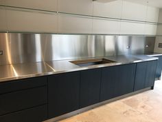 an empty kitchen with stainless steel counter tops and black cupboards on the side wall