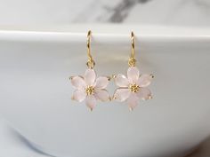 Dainty and delicate, describes these floral beauties. The flower is made from light pink, opaque zircon gemstones. The zircon is slightly faceted, to subtly reflect light. These earrings are great for someone who loves elegant minimalist jewelry. Product details: * Gold plated ear wires; Lead and nickel free * 18k gold plated setting * Light pink, opaque zircon gemstones * Handmade, with lots of love and care! - Length: 1 inch - Width:  .5 inches ❤ You can click here to see more unique jewelry from Flutterbird: https://www.etsy.com/shop/FlutterbirdCo My goal is to provide every customer with exceptional service. Please message me if you have any questions. Thank you for supporting my small business! Please visit my F.A.Q. and shop policy sections for additional info. Delicate Flower Shaped Pink Gold Jewelry, Delicate Pink Gold Flower Jewelry, Pink Flower Crystal Earrings For Gift, Pink Gold Flower Earrings As Gift, Pink Gold Flower Earrings For Gifts, Dainty Pink Flower-shaped Earrings, Dainty Pink Flower Earrings, Elegant Pink Gold Flower Earrings, Blush Flower Jewelry Gift