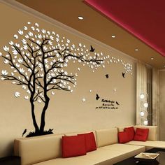 a living room with white couches and a tree painted on the wall