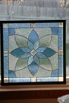 a stained glass window sitting on top of a wooden table next to a window sill