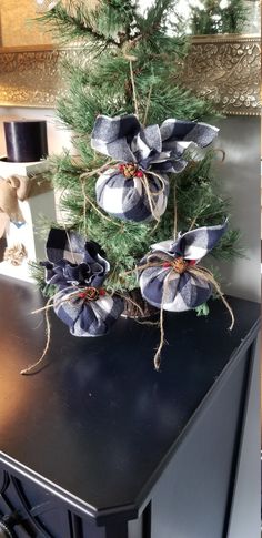 a small christmas tree with blue and white bows on it's head is sitting on a black table