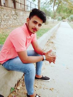 a young man sitting on the side of a road