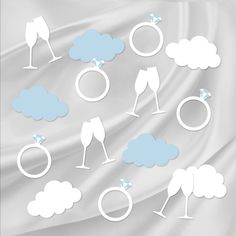 the silhouettes of wedding rings, champagne glasses and clouds are shown on a white satin background