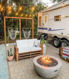 a camper trailer sits next to a fire pit in the middle of a patio