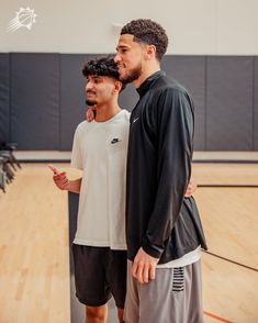 two men standing next to each other on a basketball court