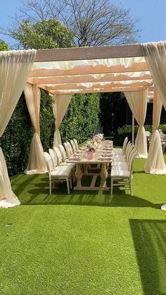 an outdoor dining area with tables and chairs covered in white draping on artificial grass