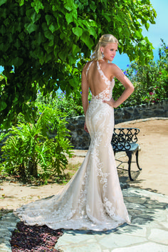 a woman standing in front of a tree wearing a dress with an open back and lace detailing