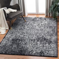 a black and white area rug with an ornate design on the floor in front of a chair