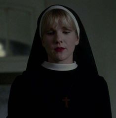 a woman with blonde hair wearing a black nun outfit