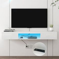 a flat screen tv mounted to the side of a white wall with a remote control