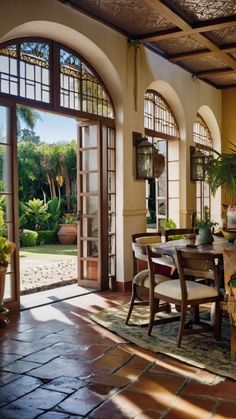 a dining room table and chairs in front of an open patio door with potted plants