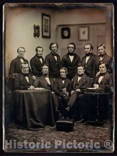 an old time photo of men in suits and ties posing for a group photo with a table