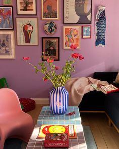 a living room with purple walls and pictures on the wall above it, along with a blue couch