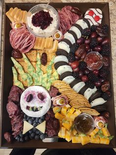 an assortment of cheeses, meats, and fruit arranged in a large tray