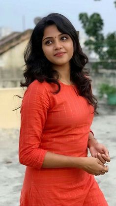 a woman in an orange dress posing for the camera with her hand on her hip