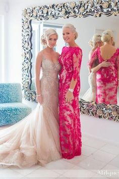 two women standing next to each other in front of a mirror