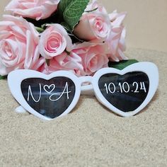 two heart shaped sunglasses with the names usa and 1044 written on them next to pink roses