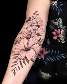 a woman's arm with flowers and leaves on it