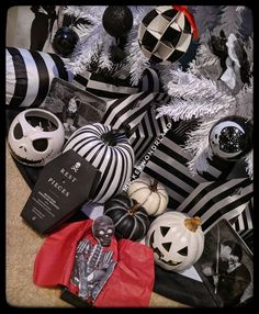 a pile of halloween decorations on top of a floor next to a christmas tree with black and white ornaments