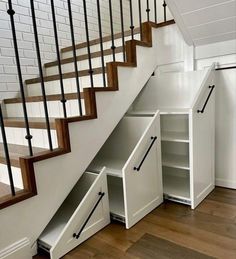 an under the stairs storage unit underneath a stair case in a white painted room with wooden floors