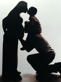 a man kissing a woman in front of a black and white photo with his shadow on the ground