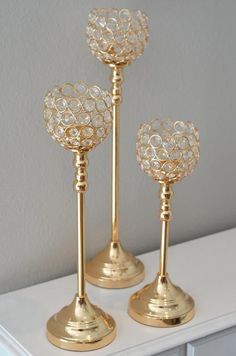 three gold candlesticks on a white table