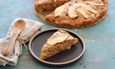 a piece of pie sitting on top of a black plate next to a wooden spoon