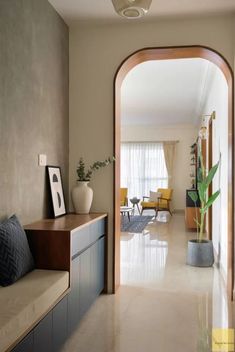 an archway leading to a living room with yellow chairs and a potted plant in the corner