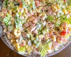 a bowl filled with pasta salad on top of a wooden table