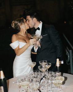 a bride and groom kissing in front of champagne glasses