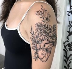 a woman's arm with flowers and a heart tattoo on the left side of her arm