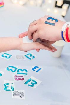 two people shaking hands over a table with numbers and letters painted on the top of them