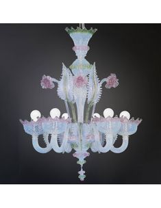 a glass chandelier with pink flowers and white balls on the bottom, in front of a black background