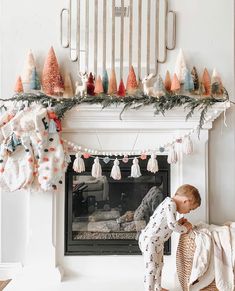 a little boy standing in front of a fire place with christmas decorations on the mantle