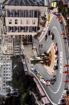 an aerial view of a race track with cars driving on it and buildings in the background