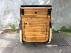 an old wooden cart sitting on top of a cement floor next to a wall and grass