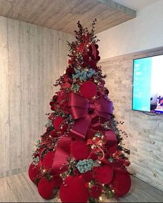 a christmas tree decorated with red bows and other holiday decorations is shown in front of a flat screen tv