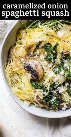 a white bowl filled with pasta, mushrooms and spinach sprinkled with parmesan cheese