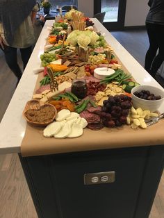 a long table filled with lots of different types of food on top of a white counter