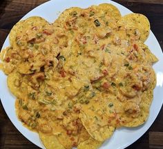 an omelet on a white plate topped with cheese and other toppings sitting on a wooden table