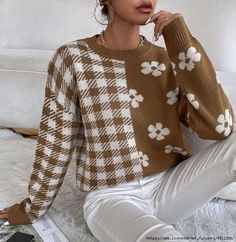 a woman sitting on the floor wearing a brown and white checkered sweater with flowers