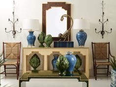 a living room with blue and white vases on the coffee table next to a mirror